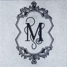 the monogrammed letter m is displayed in an ornate frame on a white tile wall