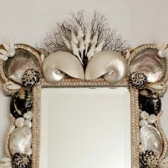 an ornate mirror with shells and seashells on the frame is hanging on a wall