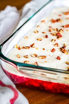 a casserole dish with nuts and cream in it on a wooden table next to a white towel