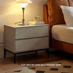 a nightstand with a lamp on top of it next to a bed