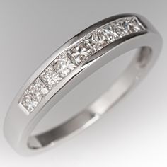 a white gold ring with princess cut diamonds on the side and channel set in the middle