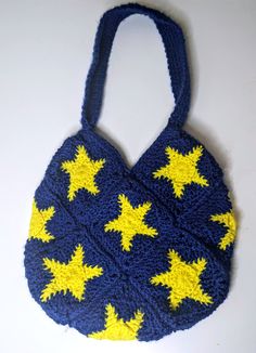 a crocheted bag with yellow stars on it sitting on a white table top