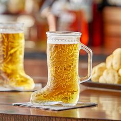 two mugs filled with beer sitting on top of a table