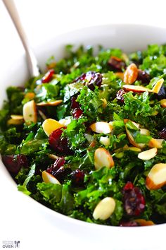 a white bowl filled with greens and nuts