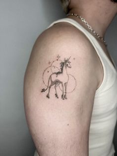 a woman's arm with a tattoo of a unicorn and stars in the sky