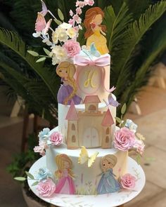 a three tiered cake with princess figurines on top and flowers in the middle