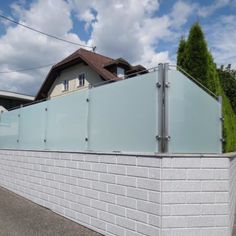 a white brick wall next to a house with a fence on the top and side