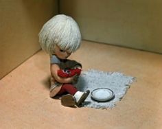 a small doll sitting on the floor holding a red object