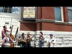 four men are playing music outside in front of a building