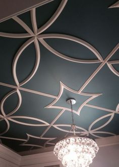 a chandelier hanging from the ceiling in a room with blue walls and white trim