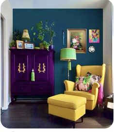 a living room with blue walls and yellow chairs in front of a purple cabinet that has pictures on it