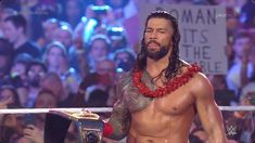 the wrestler is standing in front of a crowd with his hands on his hips and wearing a lei