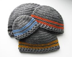 two crocheted hats are laying on top of each other, one is gray and the other is orange