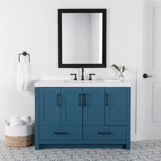 a bathroom vanity with blue cabinets and a black mirror above it, next to a white door