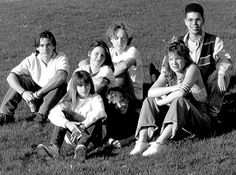 a group of people sitting on top of a lush green field next to each other