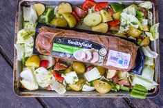 a tray filled with meat and vegetables on top of a wooden table