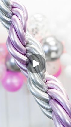 a close up of a purple and silver rope with balloons in the backgroud