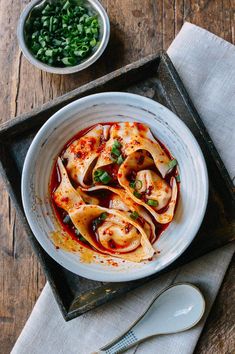 a white bowl filled with pasta and sauce on top of a wooden table