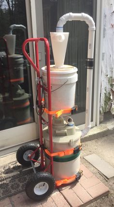 a white bucket sitting on top of a cart next to a building door and window