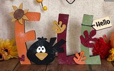 the letters are made out of wood and decorated with birds, flowers, and acorns