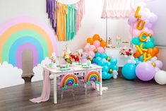 a party with balloons, streamers and rainbows on the walls is ready to be eaten