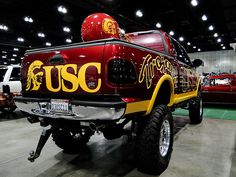 the truck is painted red and yellow with gold lettering on it's side, along with other vehicles