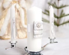 two candles are sitting next to each other on a table with christmas decorations in the background