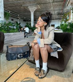 a woman sitting on top of a couch next to a purse