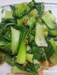 a white plate topped with green vegetables covered in sauce