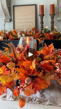 an arrangement of autumn leaves and candles on a table