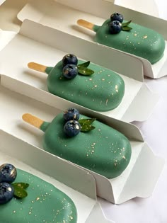 four desserts with blueberries and green leaves on them