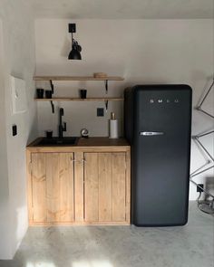 a black refrigerator freezer sitting next to a wooden cabinet in a white walled kitchen