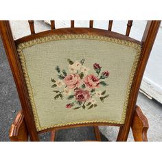 the back of a wooden chair with needled flowers on it's armrests