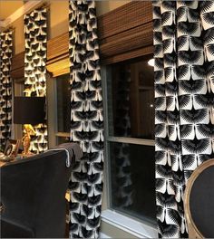 two black and white curtains hanging from the side of a window next to a chair