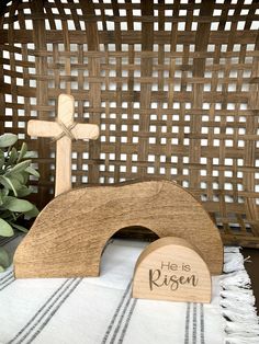 a wooden cross sitting on top of a table next to a basket filled with plants