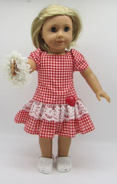 a doll with blonde hair wearing a red and white checkered dress holding a flower