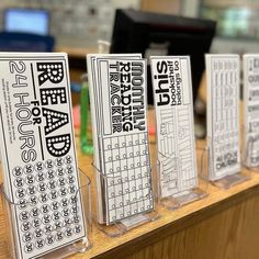 four clear acrylic stands with black and white text on them in front of a computer desk