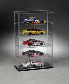 four cars in a glass display case on top of a black surface with white background