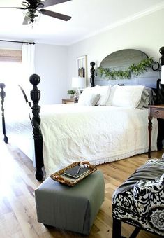 a bedroom with a bed, chair and ottoman on the hardwood floor in front of it