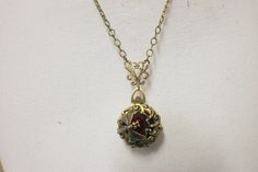 "Siam red crystal four photo locket pendant with bronze finish. Locket features a layer of bronze filigree with a s Siam red crystal set in a heart bezel the center of the locket. Wrapped around the crystal is a delicate bronze dragon fly. Locket is 1\" in diameter and hangs from a bronze filigree connector with a bronze plated chain. The chain fastens with a lobster clasp. Total pendant drop length including filigree connector is 2\" and is pictured with a 22\" chain. Please choose your chain l Red Locket Pendant Jewelry, Red Locket Jewelry With Round Pendant, Victorian Red Jewelry With Vintage Charm, Red Locket Necklace For Formal Occasions, Elegant Handmade Bronze Locket Necklace, Victorian Necklace With Detachable Pendant For Gift, Red Locket Necklace With Round Pendant, Red Locket Necklace For Wedding, Red Round Locket Jewelry