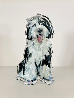 a small white and black dog sitting on top of a table next to a wall