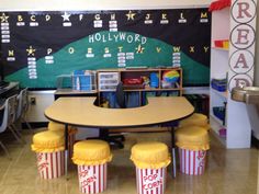 a classroom with popcorn themed desks and chalkboard on the wall, along with two yellow stools