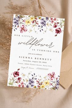 a wedding card with flowers on it sitting next to some brown paper and an envelope