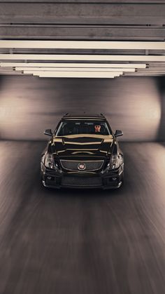 a black car driving through a tunnel with lights on it's headlamps