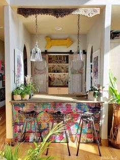 a colorful bar with two stools in front of it and plants on the counter