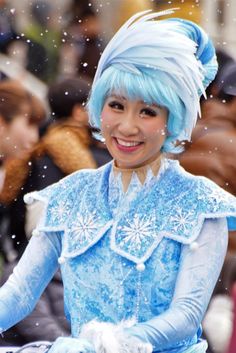 a woman dressed in blue and white with snow flakes on her head, smiling at the camera