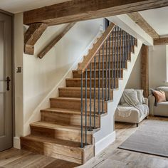 a living room filled with furniture and a stair case next to a couch on top of a hard wood floor