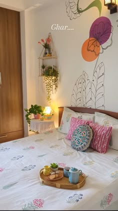 a bed with flowers painted on the wall behind it and a tray full of tea