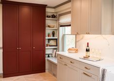 a kitchen with white cabinets and wine bottles on top of the cupboards in it