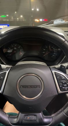 the steering wheel and dash board of a car in a showroom with other vehicles